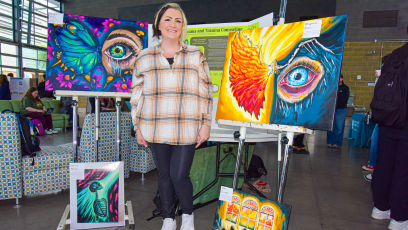 CGCC student poses with her original paintings at the Honors & HIPs Showcase