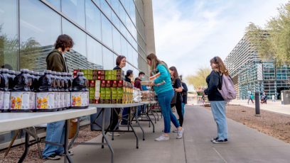 People picking up food items from tables at CGCC's Pecos campus during a monthly produce distribution