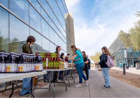 People picking up food items from tables at CGCC's Pecos campus during a monthly produce distribution