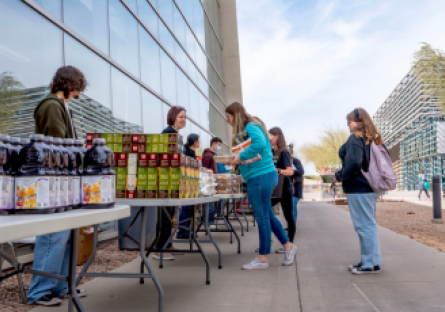People picking up food items from tables at CGCC's Pecos campus during a monthly produce distribution