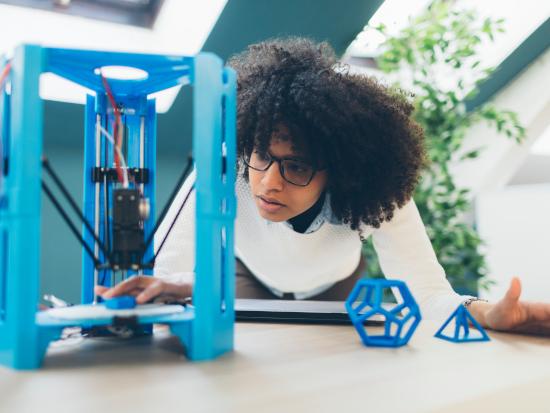 Student working with a 3D printer in a lab, designing and producing a digital fabrication project.