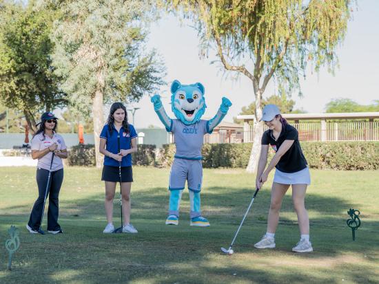 Three women playing golf with Codi, the CGCC mascot, at the 2026 Swing 4 SWE event