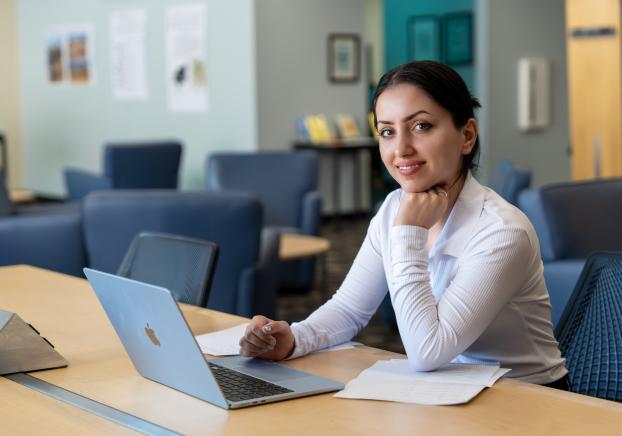 Female student on laptop at table.