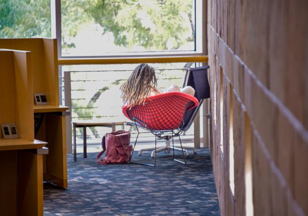 Student seated in a chair facing a window in the Pecos Library