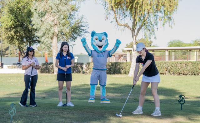 Three women playing golf with Codi, the CGCC mascot, at the 2026 Swing 4 SWE event